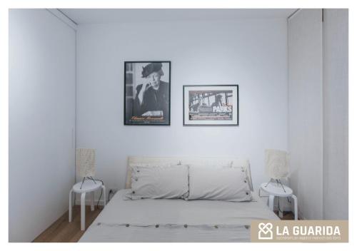 a white bedroom with a bed and two pictures on the wall at Relais Giusti 2 - La Guarida in Udine