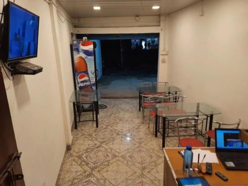 a room with tables and chairs and a flat screen tv at Sukun Guest House in Siliguri