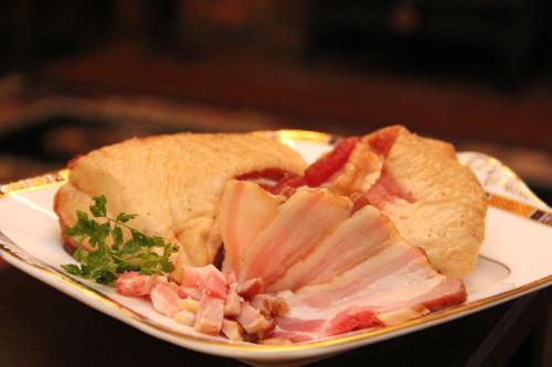 a sandwich on a plate with meat and bacon at Hakuba Skala Inn in Hakuba