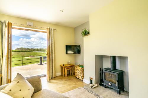 a living room with a wood stove and a balcony at Brecks Farm - Well Cottage in York