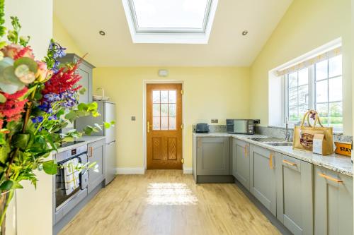 a kitchen with gray cabinets and a skylight at Brecks Farm - Well Cottage in York