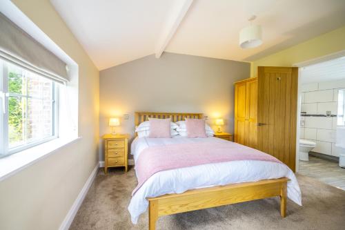 a bedroom with a large bed and a window at Brecks Farm - Well Cottage in York