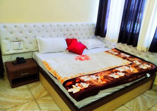 a bed with a white headboard and red pillows at Hotel vinayak inn in Haridwār