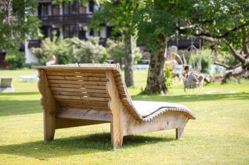 a wooden bench sitting in the grass in a park at Adolphine Garden in Rottach-Egern