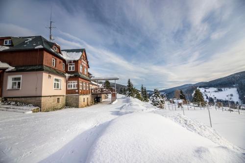 a house in the snow in front of a mountain at penzion Vysoká Stráž in Pec pod Sněžkou