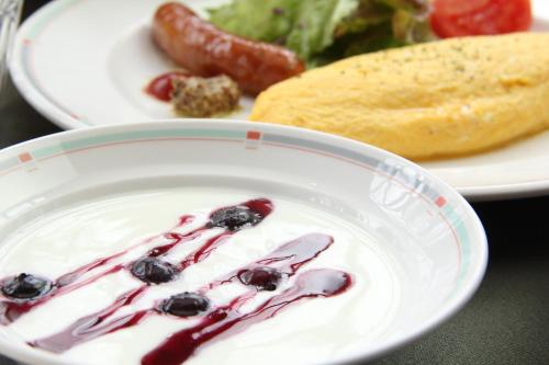 a bowl of yogurt with blueberries and a plate of food at Hakuba Skala Inn in Hakuba