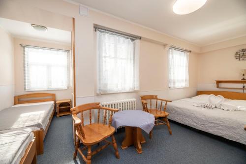 a room with two beds and chairs and windows at penzion Vysoká Stráž in Pec pod Sněžkou