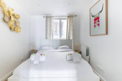 une chambre blanche avec deux lits et une fenêtre dans l'établissement Appartement Grands Boulevards - 21 -, à Paris