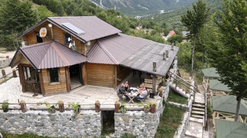 two people sitting at a table in front of a house at Thethi Paradise Hotel & Restaurant in Theth
