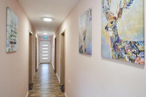 a hallway with three paintings on the walls at Thermal Apartman - EM in Gárdony