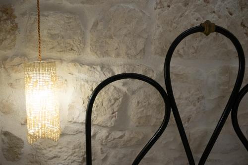 a chandelier hanging from a wall with a stone wall at Casa Sotto l'Arco in Ceglie Messapica