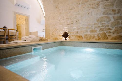 een groot zwembad in een kamer met een stenen muur bij Casa Sotto l'Arco in Ceglie Messapica