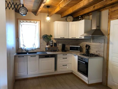 une cuisine avec des armoires blanches et un four à plaques de cuisson dans l'établissement Gite des petites fayes sud, à La Douze