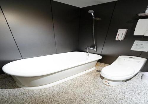 a bathroom with a toilet and a bath tub at Walker Hotel - Sanchong in Taipei