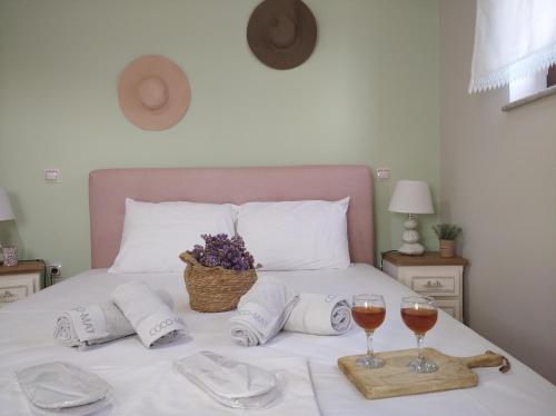 a bed with two glasses of wine and towels at Paliokaliva Home in Roussopoúlion