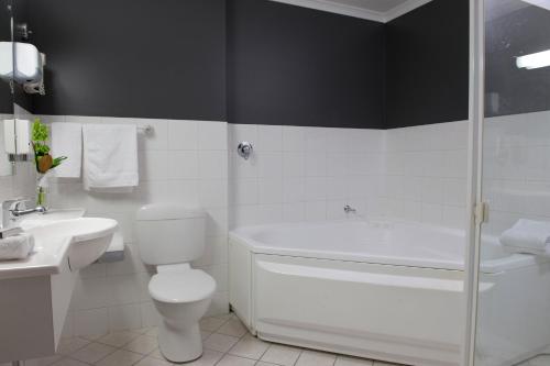 a bathroom with a toilet and a sink and a shower at Adelaide Riviera Hotel in Adelaide
