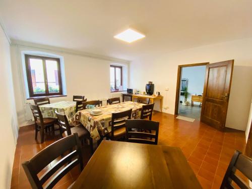 a dining room with tables and chairs and a kitchen at Casa delle Giuggiole in Dogna