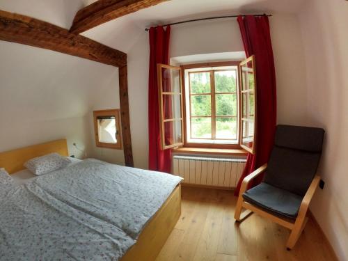 a bedroom with a bed and a chair and a window at Juvanova hous - rooms in Luče
