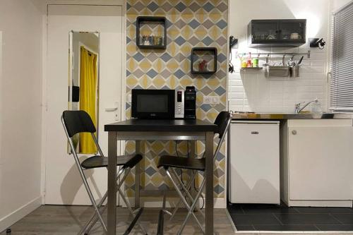 eine Küche mit einem Tisch und einer Mikrowelle in der Unterkunft Charmant studio hypercentre in Rouen