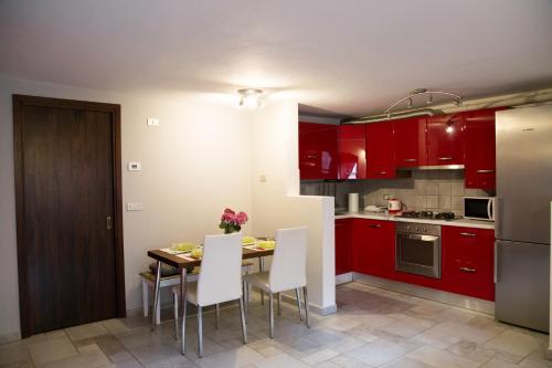 a kitchen with red cabinets and a table with white chairs at Maison Poppy in Aosta