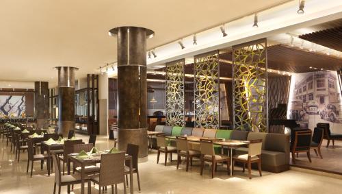 a restaurant with tables and chairs in a building at Hotel Santika Premiere Kota Harapan Indah in Bekasi