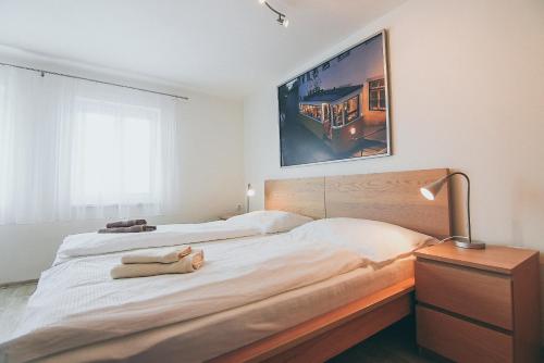 Vila Šumná في لوهاتشوفيتسا: غرفة نوم بسرير كبير عليها لوحة كبيرة على الحائط