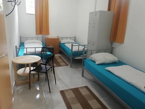 a room with three beds and a table and chairs at The Hostel in Hamburg