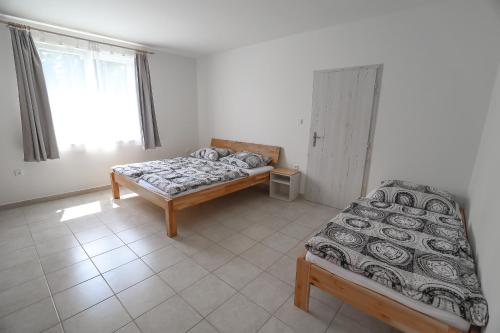 a bedroom with two beds and a window at Chaty a Apartmány Hracholusky Kemp Kosatka in Pňovany