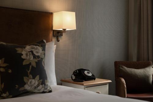 a bed with a white comforter and a lamp at The Glencoe Inn in Glencoe