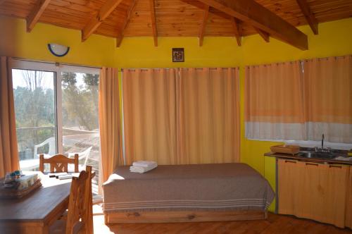 a bedroom with a bed and a desk and a window at Cabañas Kumelkalechi in Los Reartes