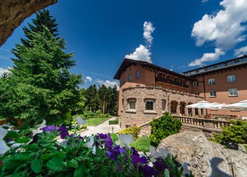 a large brick building with flowers in front of it at Spa Hotel Dvoretsa in Velingrad