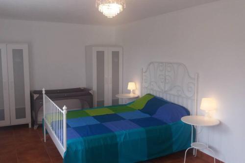 um quarto com uma cama com um cobertor azul e verde em casa das laranjeiras em Abragão