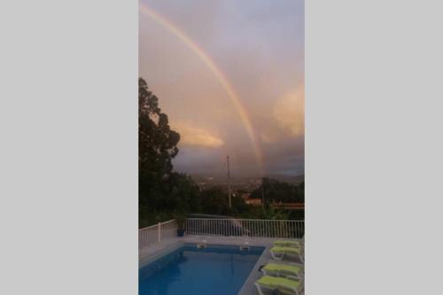 a rainbow in the sky over a swimming pool at casa das laranjeiras in Abragão