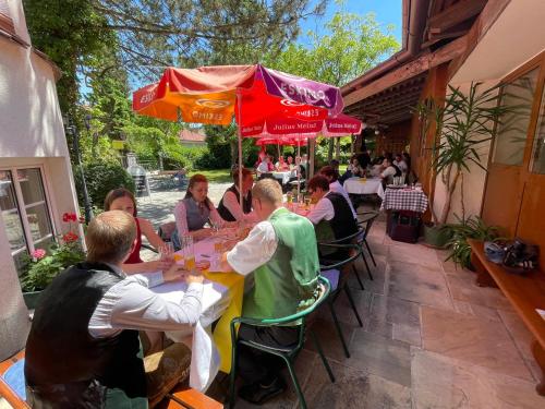 a group of people sitting at a table under an umbrella at Hotel - Landgasthof Winklehner in Sankt Pantaleon-Erla
