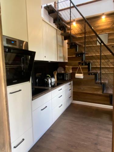 a kitchen with white cabinets and a spiral staircase at Domek pod lasem in Kołczygłowy