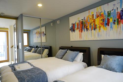 een slaapkamer met drie bedden en een schilderij aan de muur bij 新築一軒家 東京ヴィラ リバーサイド平井 in Tokyo