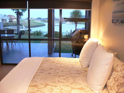 a bedroom with a bed with a view of a balcony at Sovereign Pier On The Waterways in Whitianga