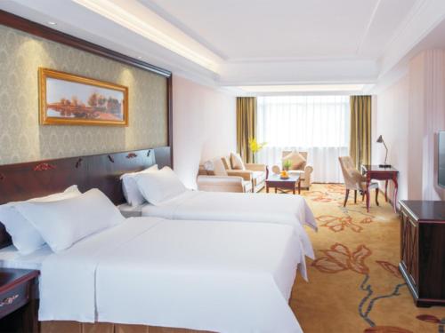 a hotel room with two beds and a living room at Vienna Hotel Shenzhen Shiyan Shilong Community in Bao'an