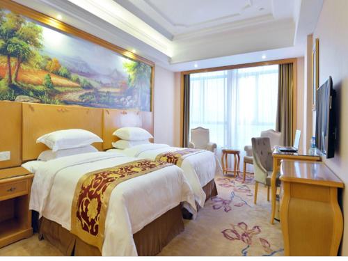 a hotel room with two beds and a television at Vienna International Hotel Meizhou Dingzi Bridge in Meizhou