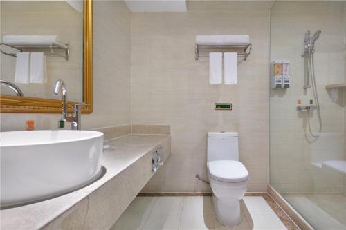 a bathroom with a sink and a toilet and a shower at Vienna Hotel Zhengzhou Zhongyuan Futa in Zhengzhou