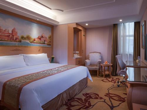 Una habitación de hotel con una cama grande y una silla. en Vienna International Hotel Shenzhen Jingtian, en Shenzhen