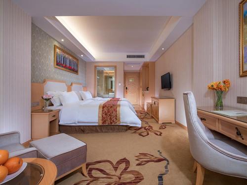 FenghuangweiにあるVienna Hotel Shenzhen Fuyong Villageのベッドとリビングルームが備わる広いホテルルームです。