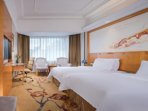a hotel room with a large bed and a large screen at Vienna International Hotel Zhuhai Golden Phoenix in Zhuhai