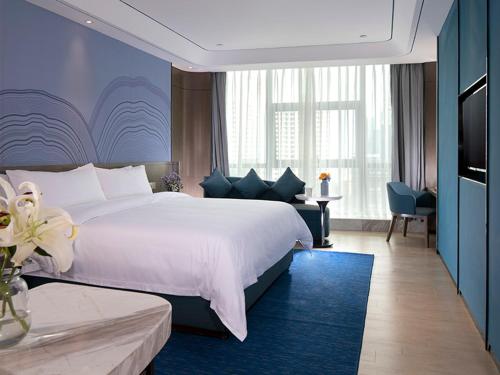 a bedroom with a large white bed and a blue wall at Vienna Hotel(Haikou International Convention and Exhibition Center) in Haikou