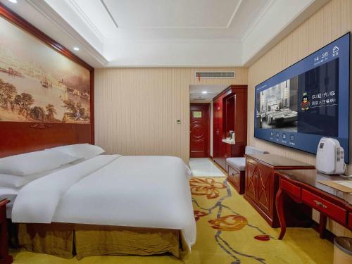a bedroom with a large bed and a flat screen tv at Vienna Hotel Anhui Hefei Sanxiaokou in Hefei