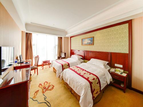 a hotel room with two beds and a television at Vienna Hotel Shanghai Jiading New City in Shanghai