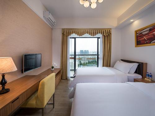 恵州市にあるVienna International Hotel Huizhou Daya Bay Century Cityのベッド2台とテレビが備わるホテルルームです。