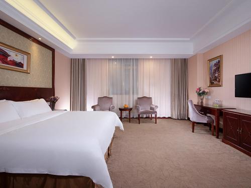 een hotelkamer met een groot bed en een bureau bij Vienna Hotel Guangzhou Panyu NanCun in Guangzhou