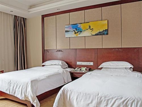 a hotel room with two beds and a wall at Vienna Hotel Jiangyin Qishan Road in Jiangyin