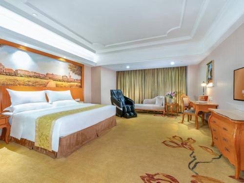 Guigang的住宿－維也納國際酒店廣西貴港荷城路店，酒店客房设有一张大床和一张书桌。